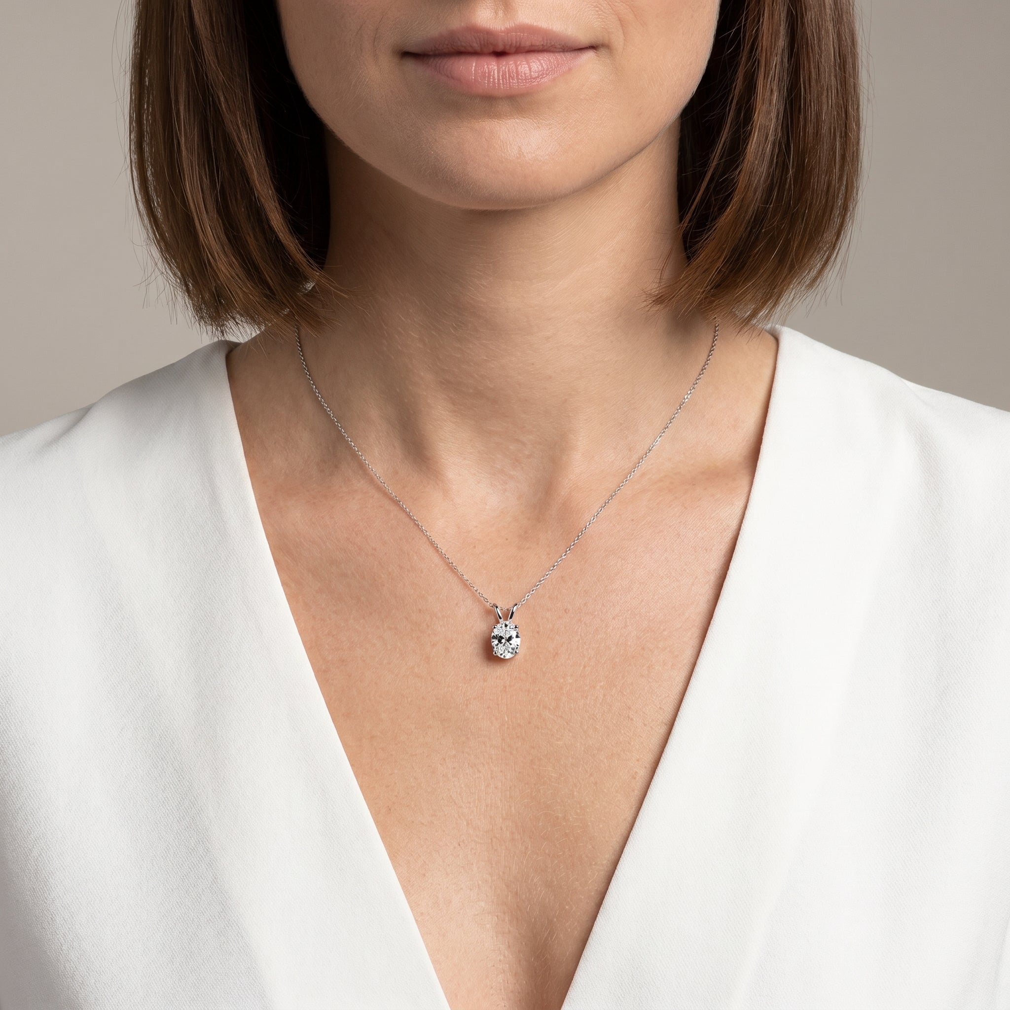 Model wearing 1 carat oval moissanite pendant necklace in 925 silver white V-neck styling