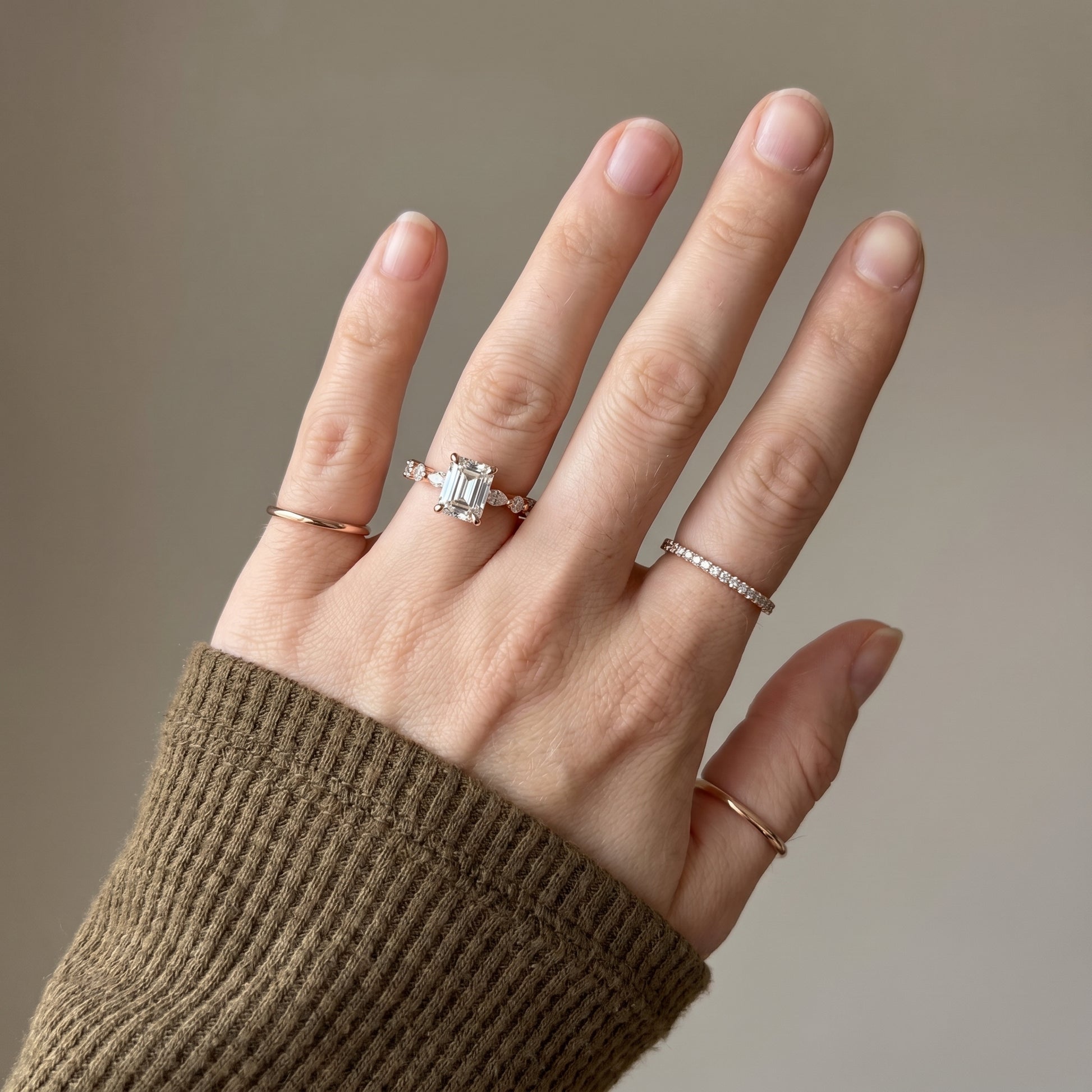 Emerald cut moissanite ring worn on hand with hidden halo and yellow gold finish