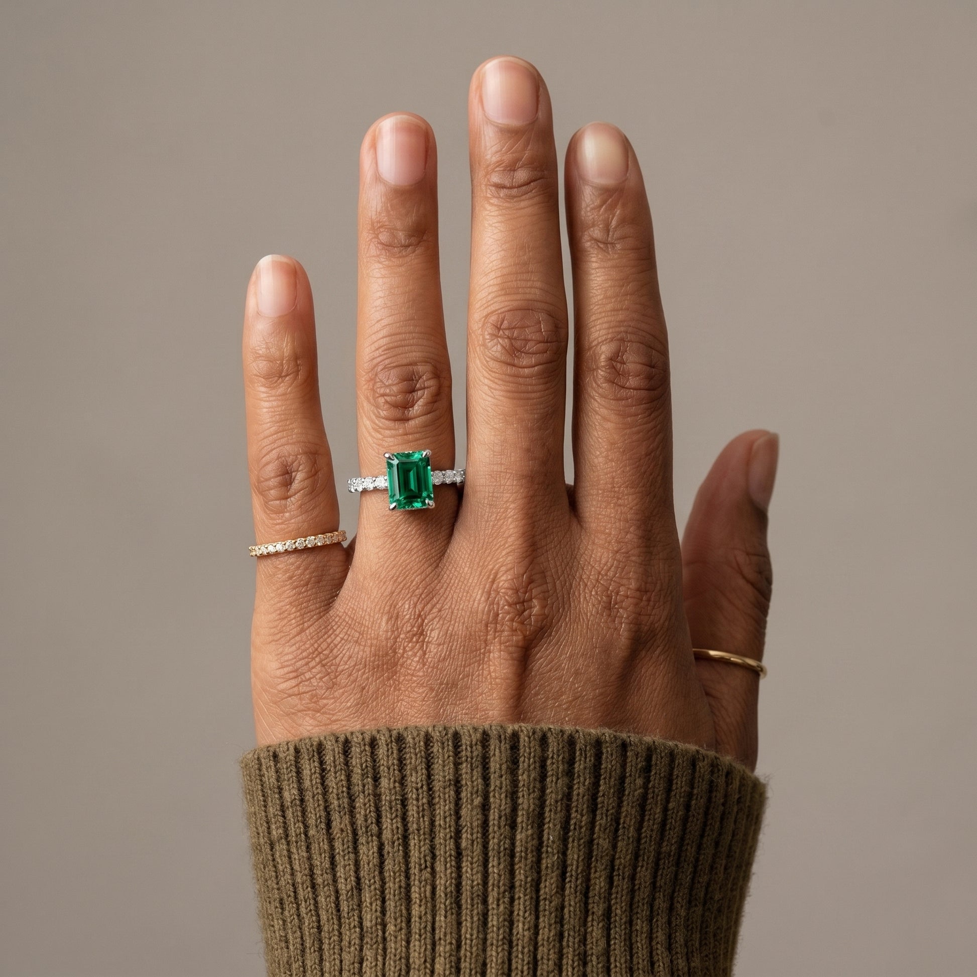 Emerald cut green moissanite ring worn on hand with pavé band in silver
