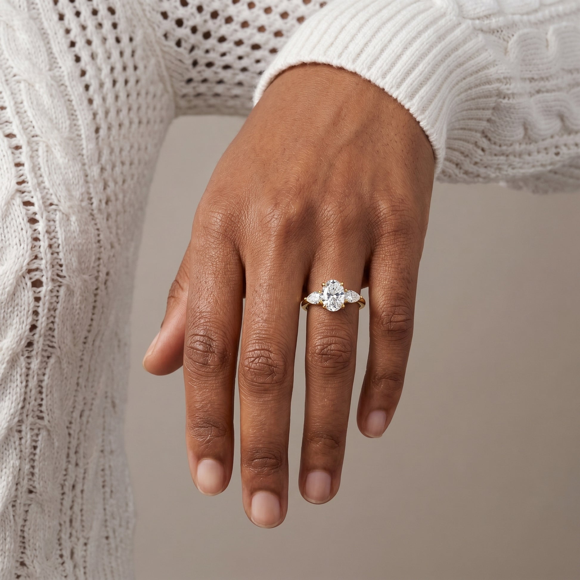 Close up hand shot of oval moissanite three stone ring yellow gold plated silver sparkling bridal jewelry