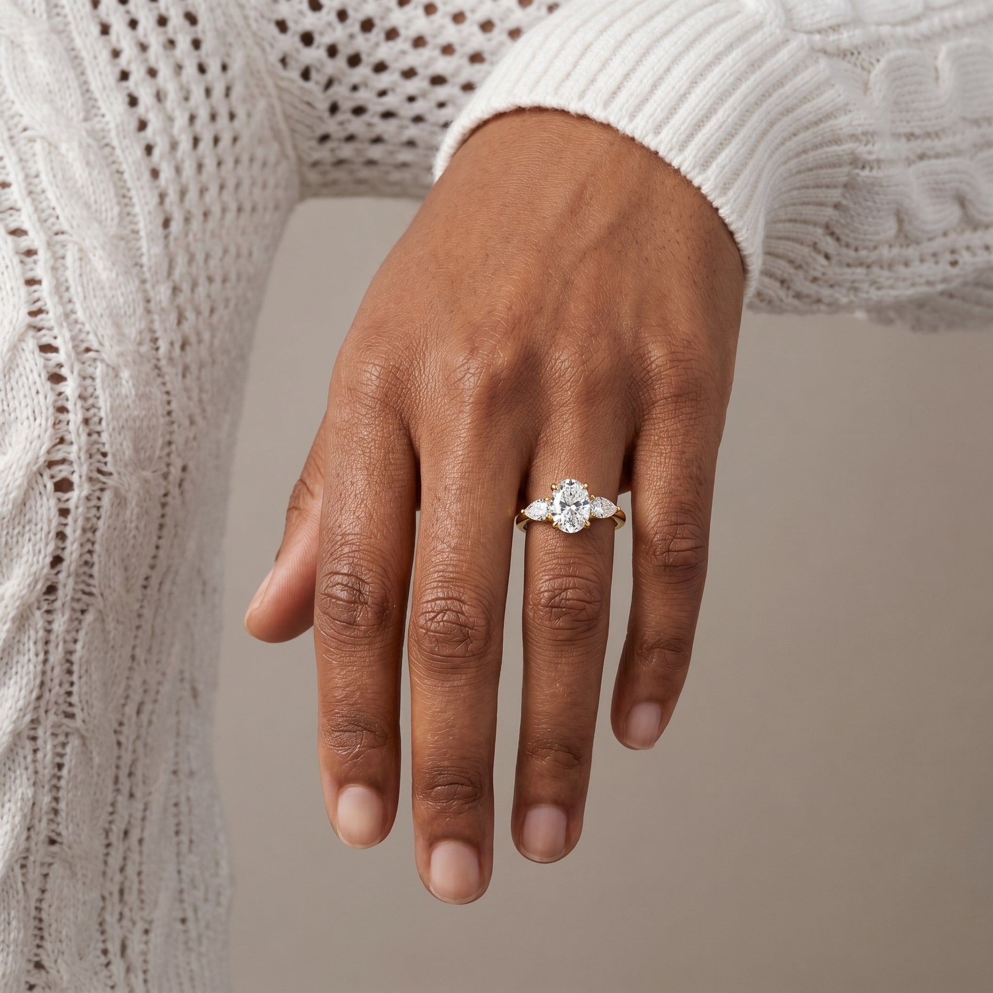 Close up hand shot of oval moissanite three stone ring yellow gold plated silver sparkling bridal jewelry
