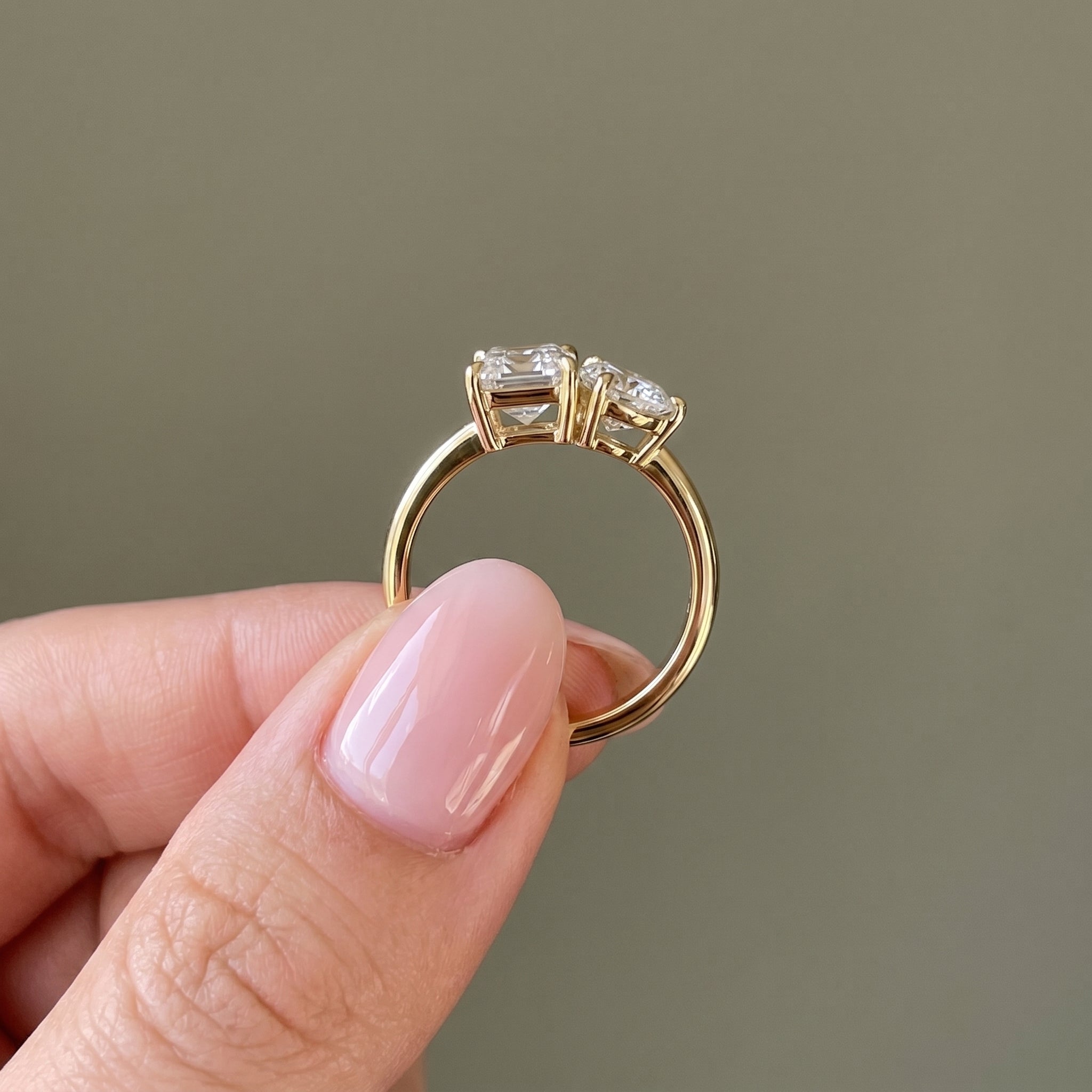 Side view of emerald and round cut moissanite Toi et Moi ring gold finish