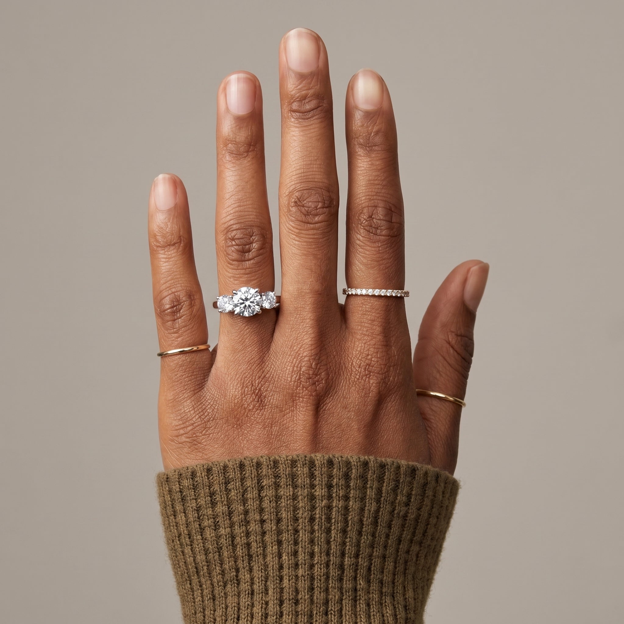 woman wearing 3 stone moissanite engagement ring silver band round cut diamond luxury bridal jewelry