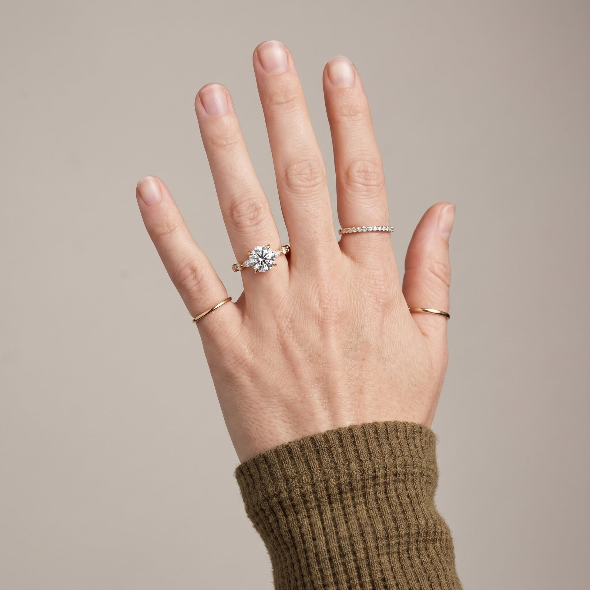 Luxury moissanite solitaire ring worn on hand with yellow gold band and hidden halo