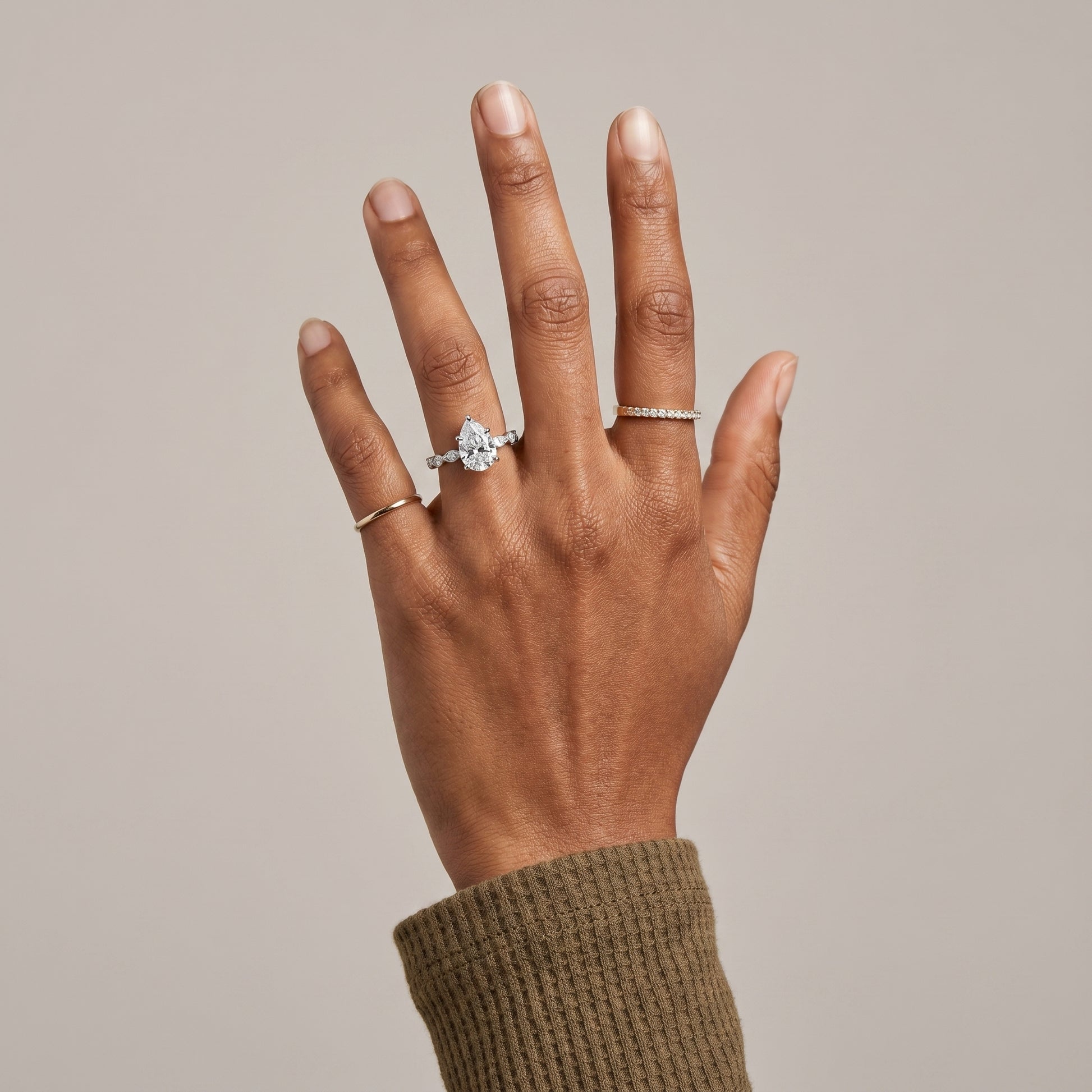 Pear cut moissanite ring worn on hand in 925 sterling silver with hidden halo
