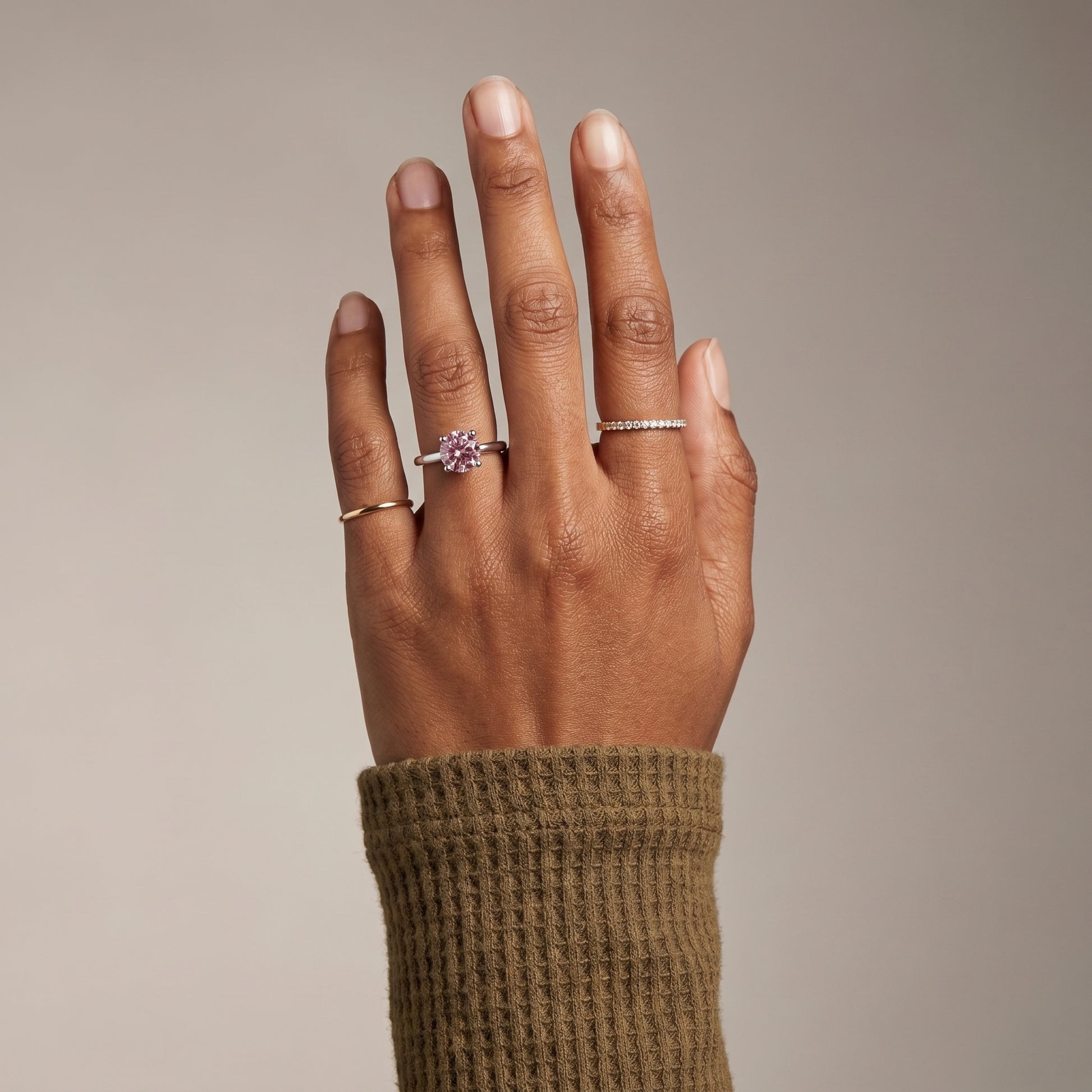 Pink moissanite solitaire ring on hand in 925 sterling silver styled with minimalist stacking rings