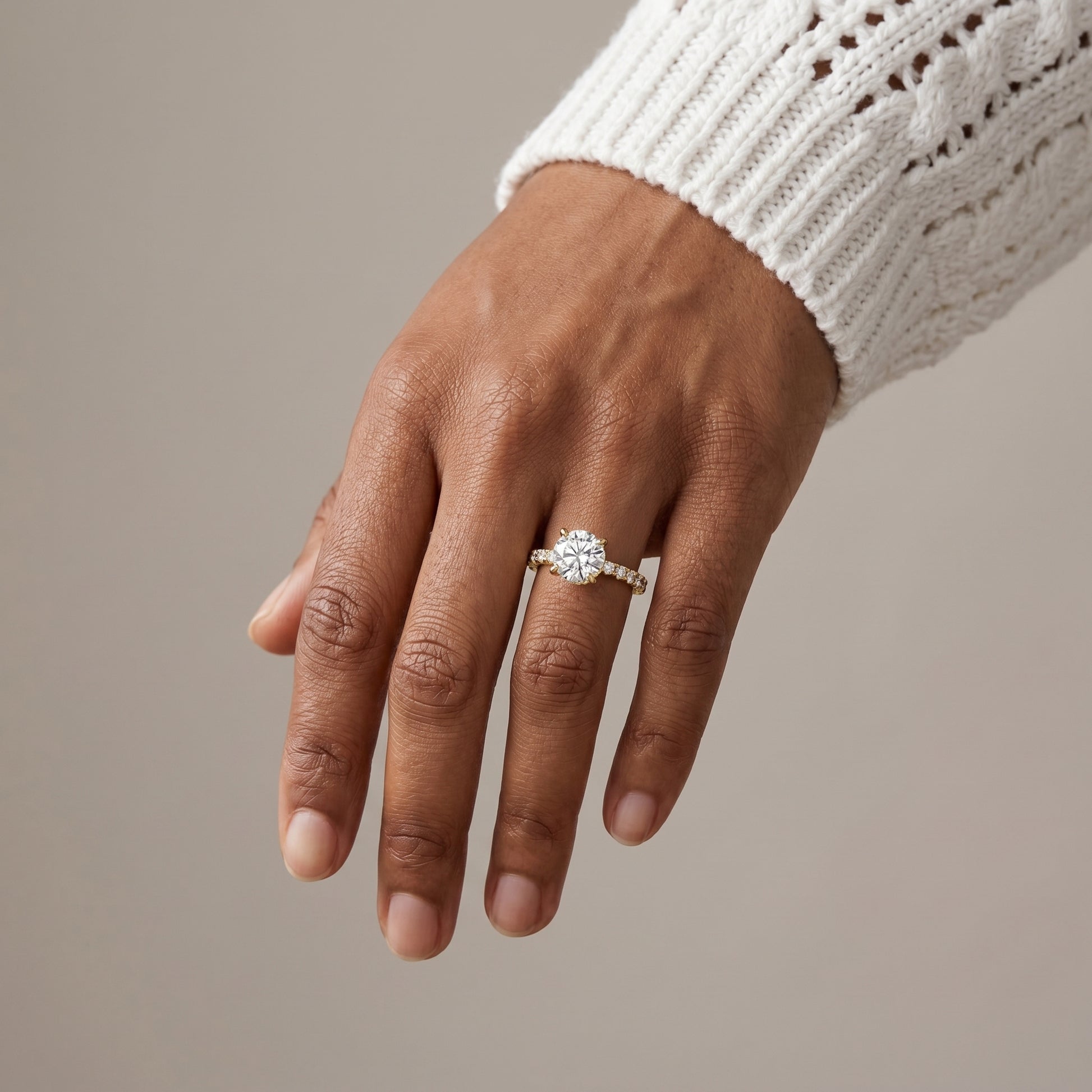 Round moissanite engagement ring in sterling silver with pavé band in natural light

