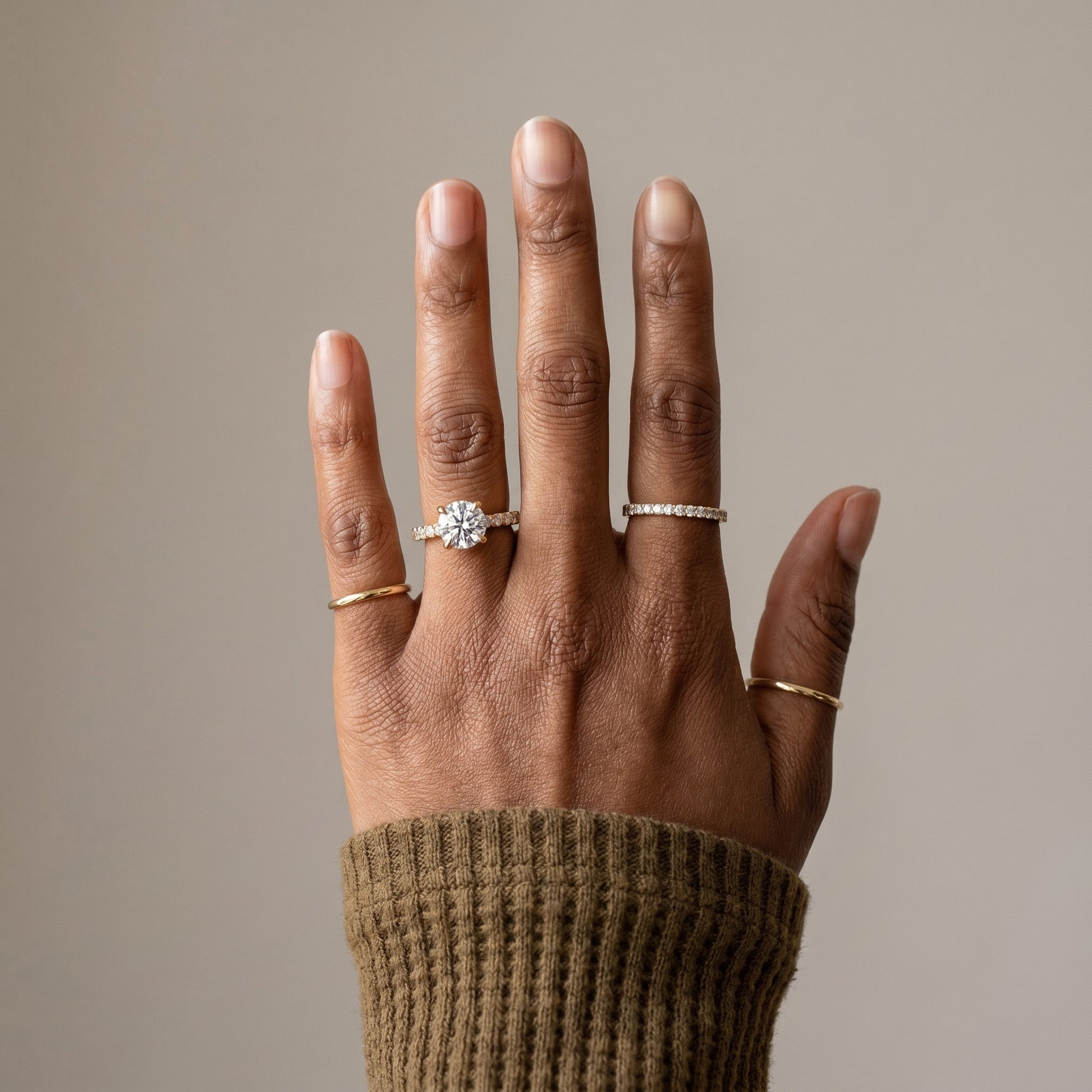 Round cut moissanite ring worn on hand with pavé band in 925 sterling silver
